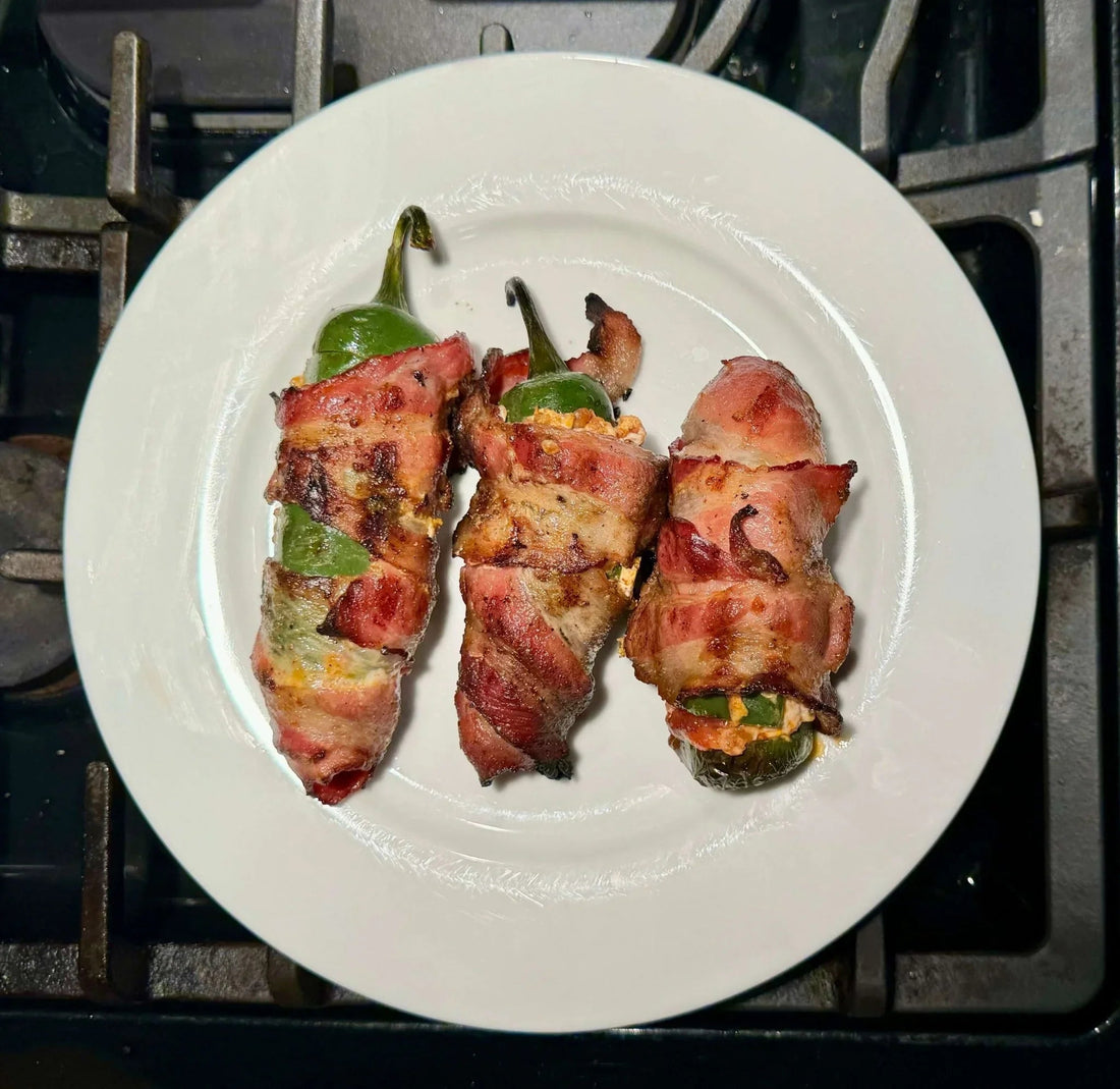 Three bacon-wrapped jalapeño poppers on a white plate, fresh from the oven