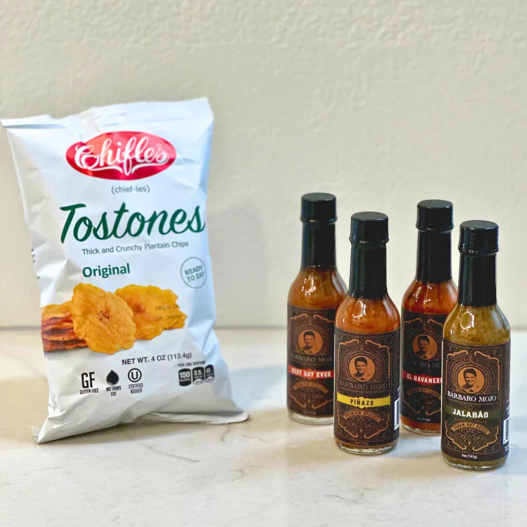 Bag of Chifles tostones plantain chips next to four bottles of Barbaro Mojo Cuban hot sauce on a kitchen counter